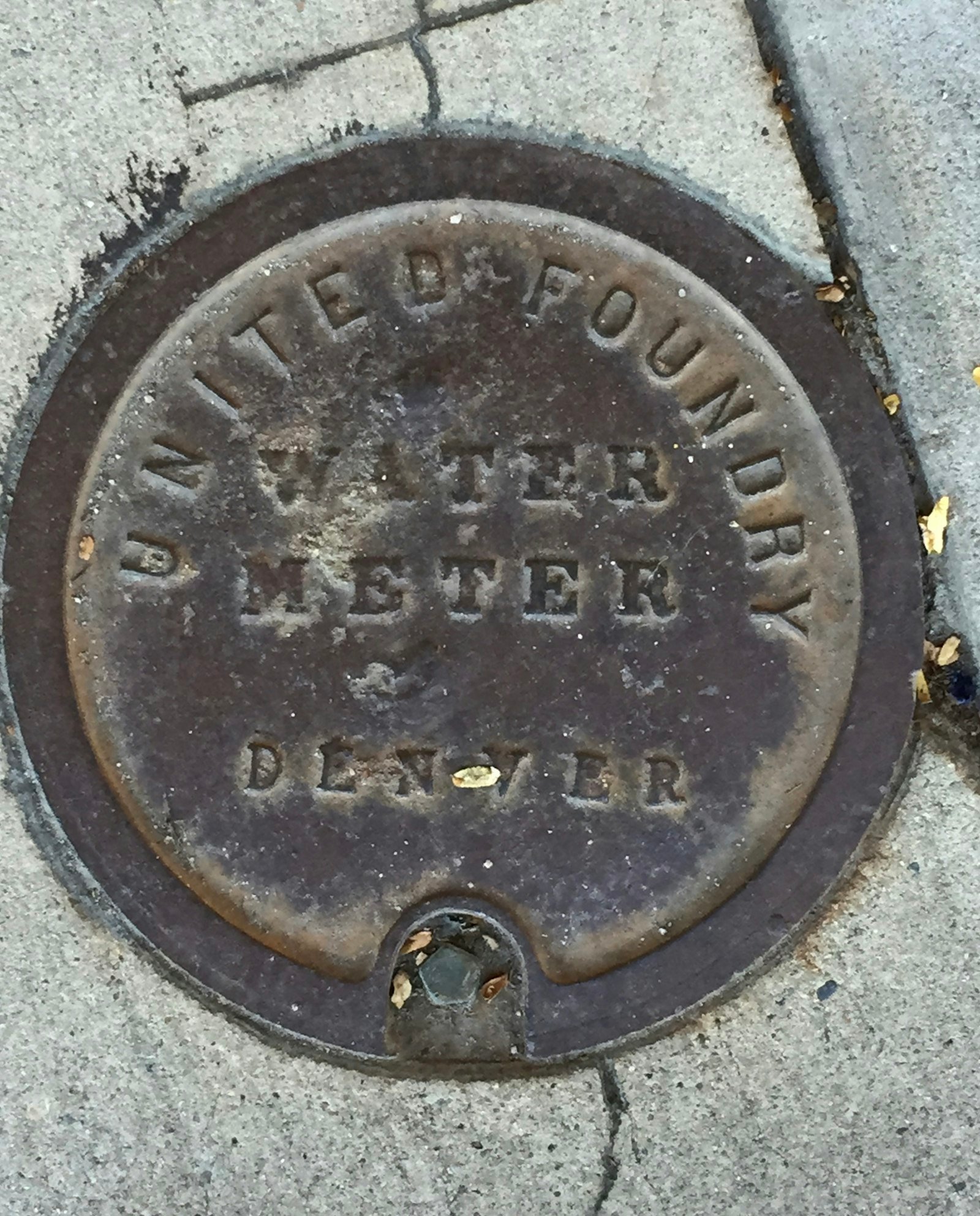 Manhole cover on a sidewalk, representing sewer line repair in San Antonio TX